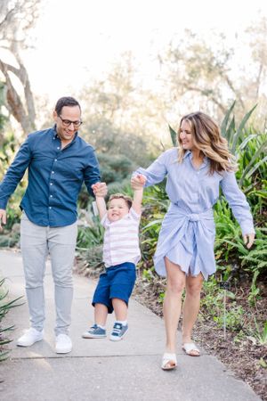 Family walking and playing together on a garden path during an outdoor photo session.