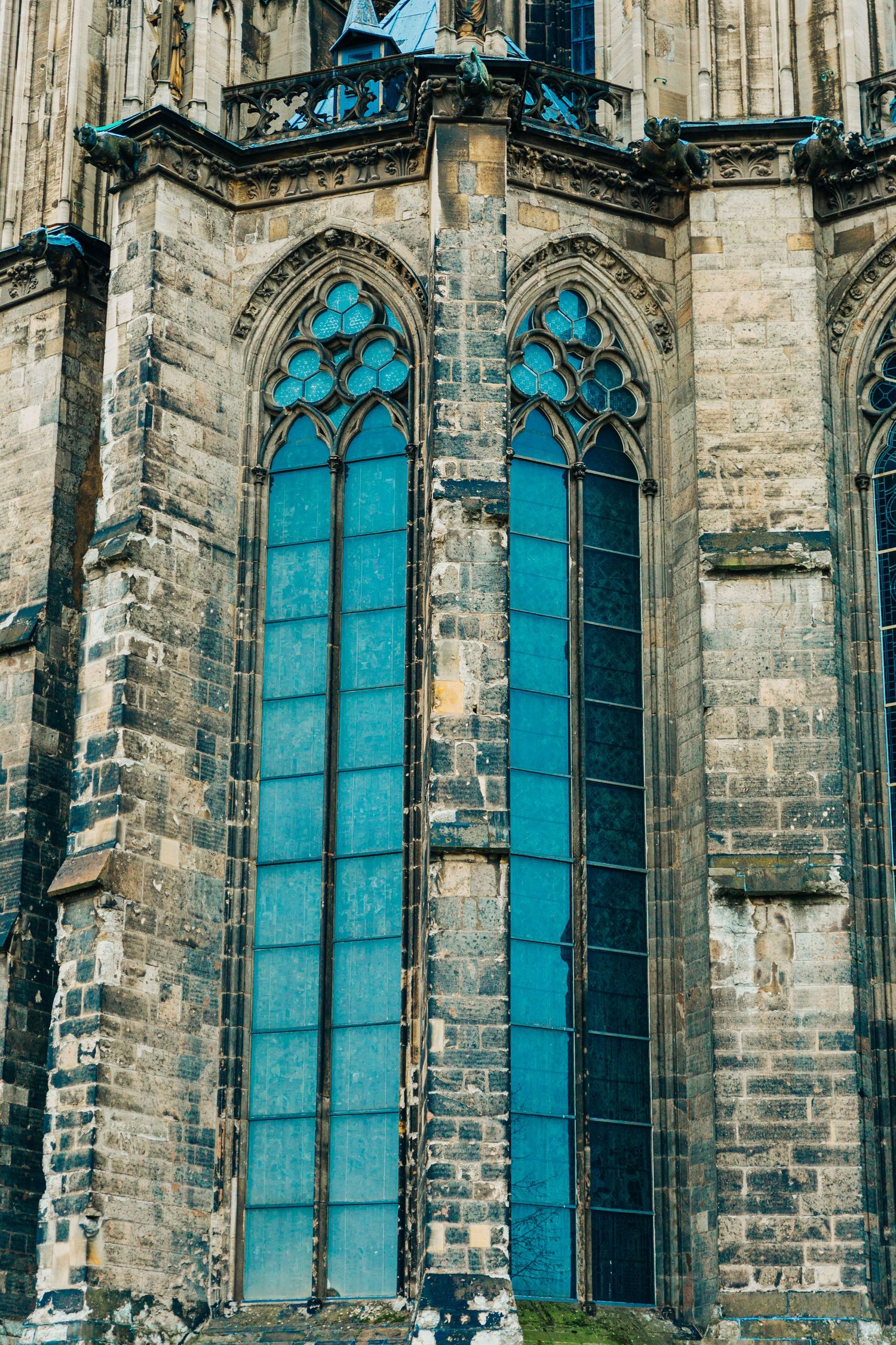 Tall stained glass windows with Gothic tracery and blue tint at Cologne Cathedral.