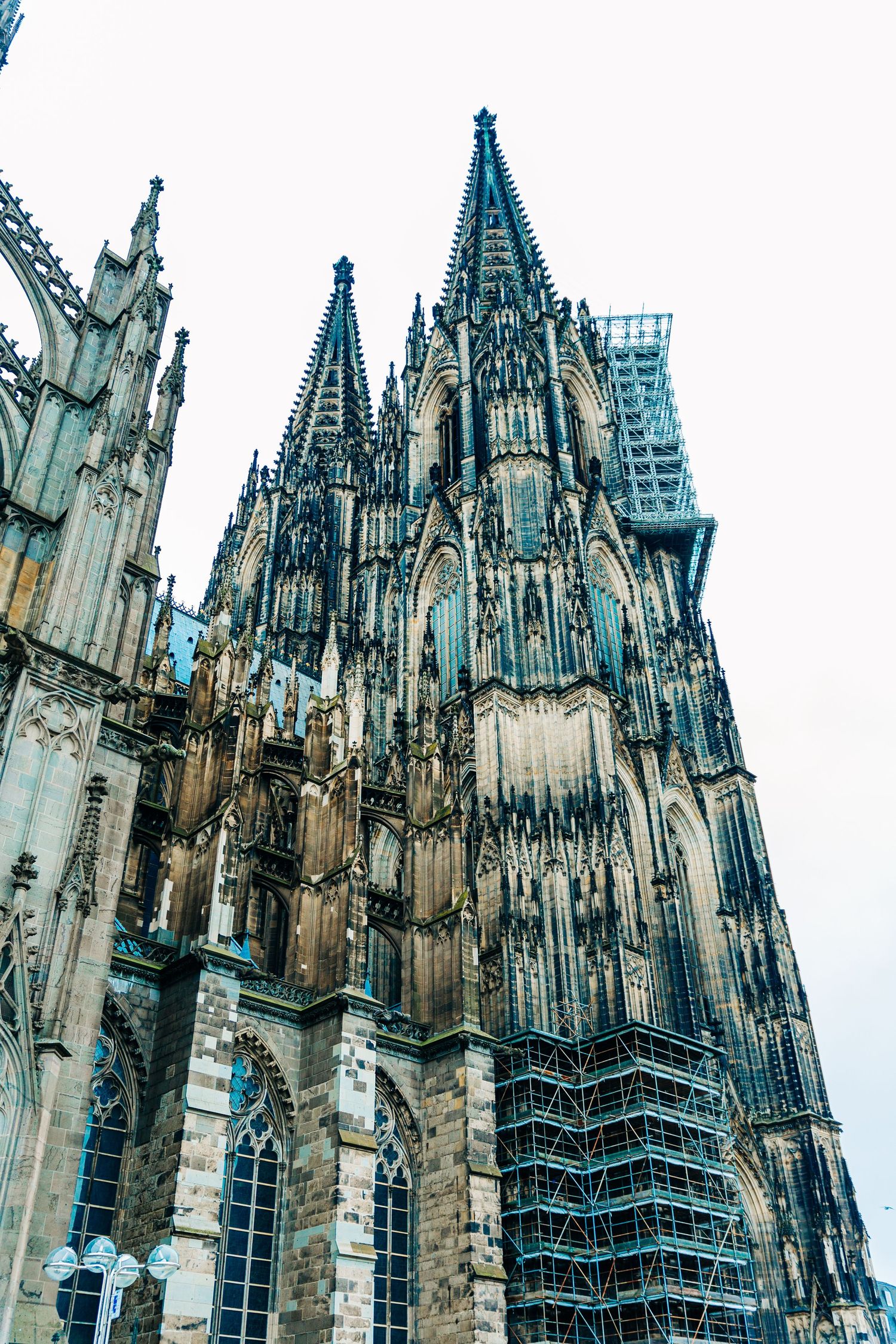 Towering spires and ornate stonework of Cologne Cathedral with scaffolding visible.