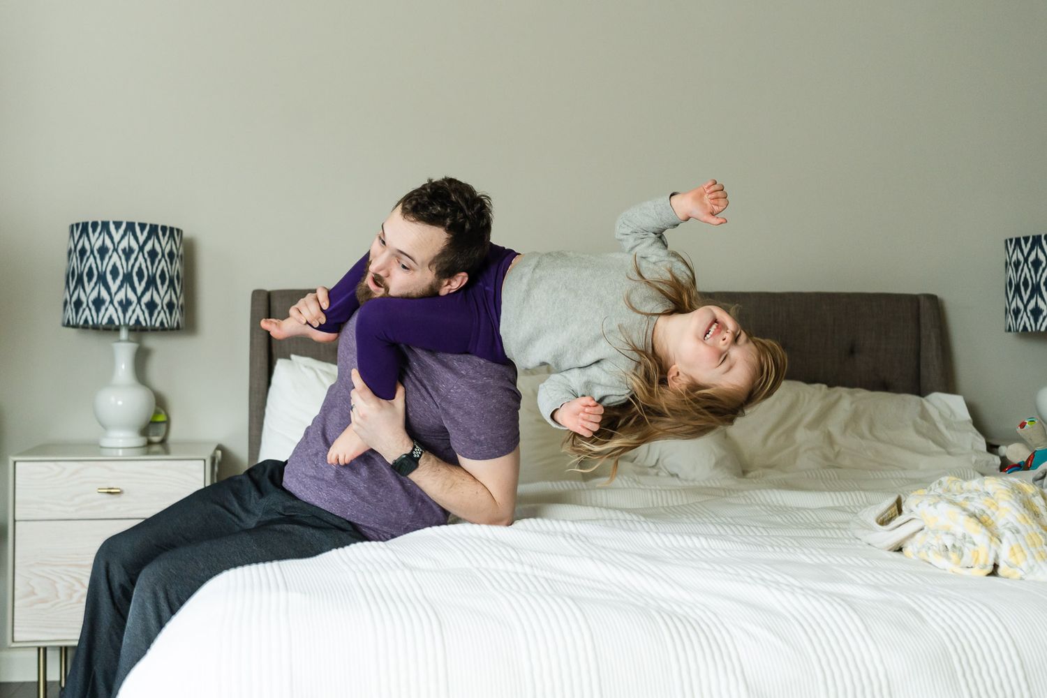 Family playing together on the bed during newborn photos.