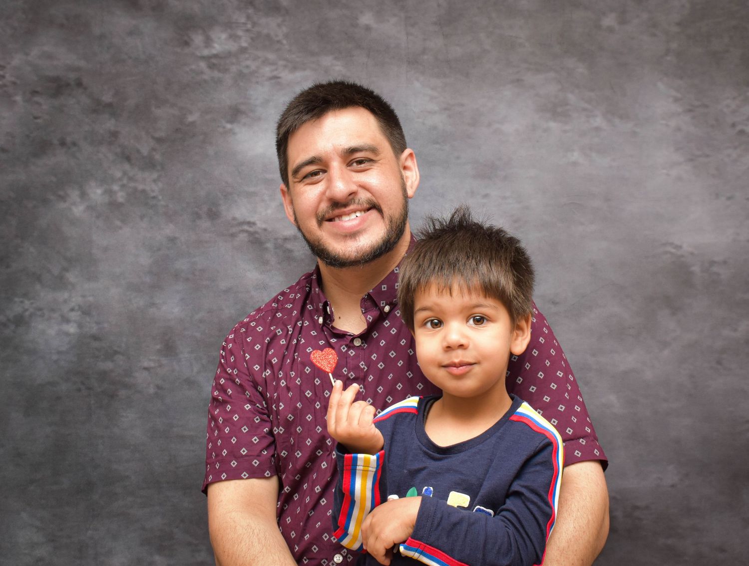 A sequence of playful studio portraits showing family bonding moments against a gray backdrop.