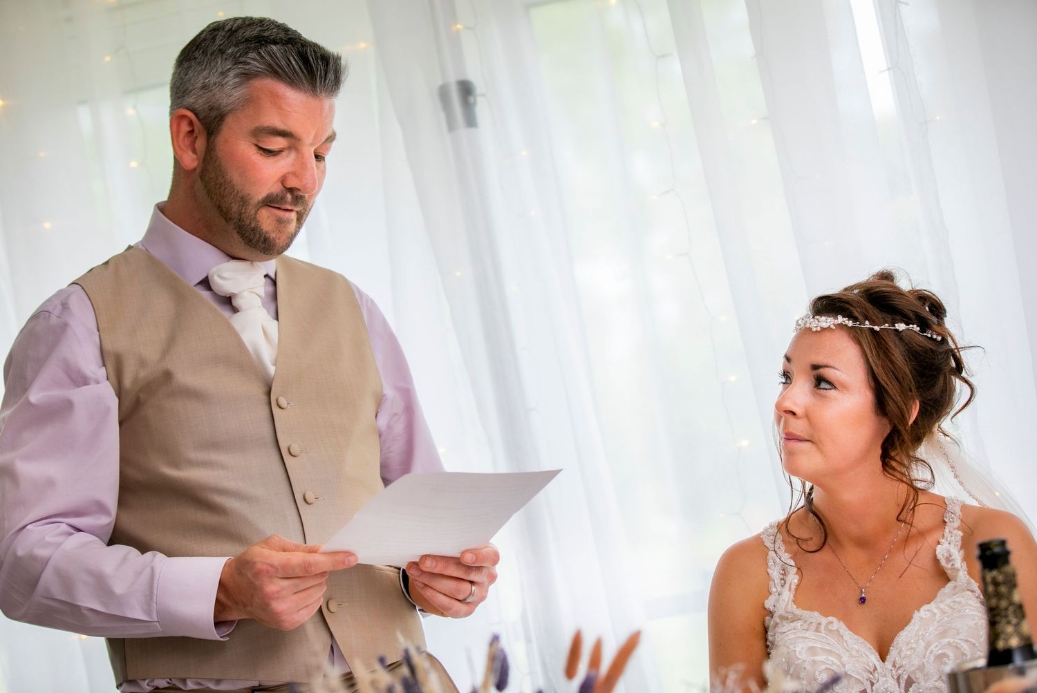 Wedding speeches and toasts being delivered during an indoor reception with white draping.
