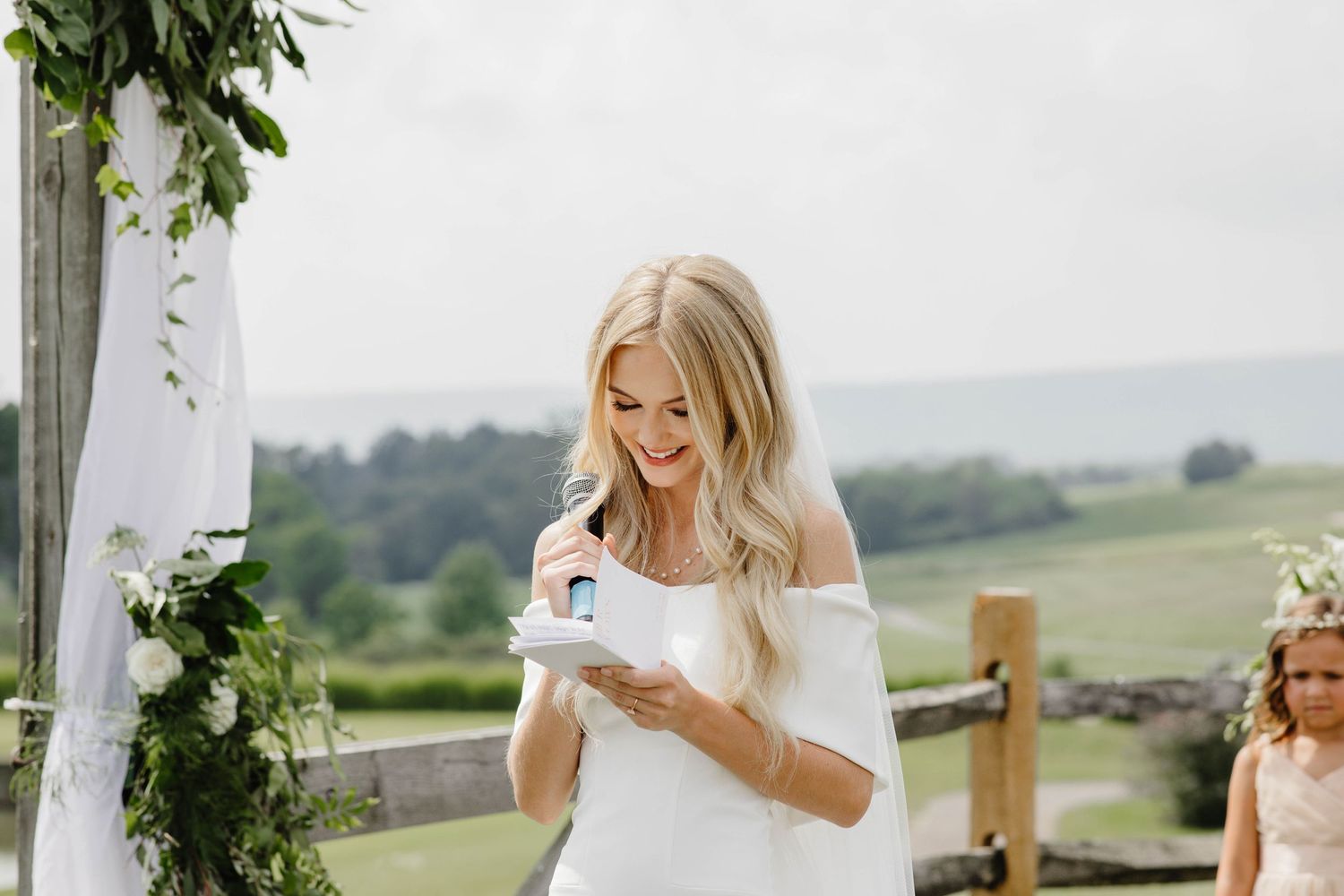 Wedding guests reading messages in an outdoor venue decorated with greenery.