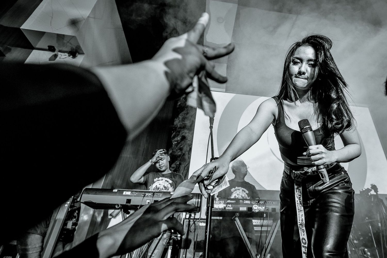 Black and white concert photo showing performer with audience members holding up phones.
