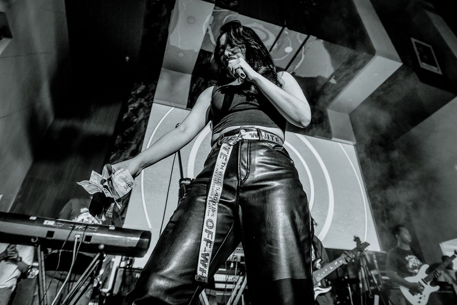 Black and white shot of a performer singing intensely into a microphone on stage.