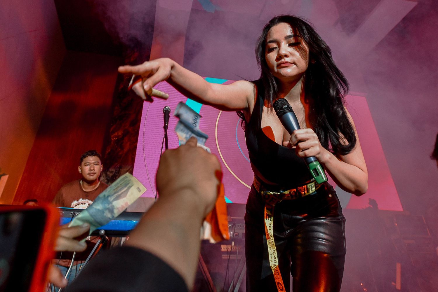 Dynamic performance shot with artist engaging crowd amid colorful stage lighting.