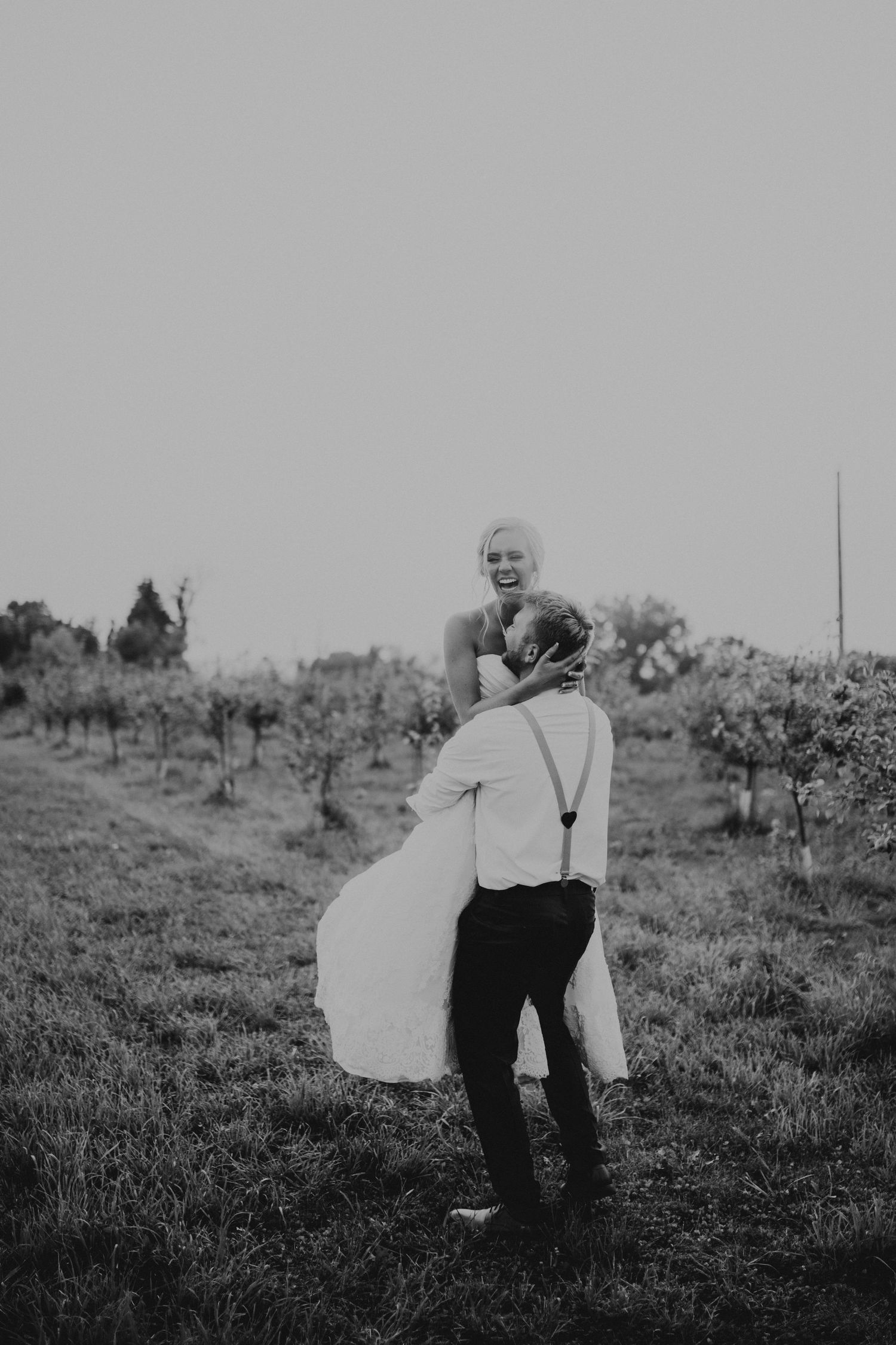 Black and white photo of couple embracing in a vineyard.
