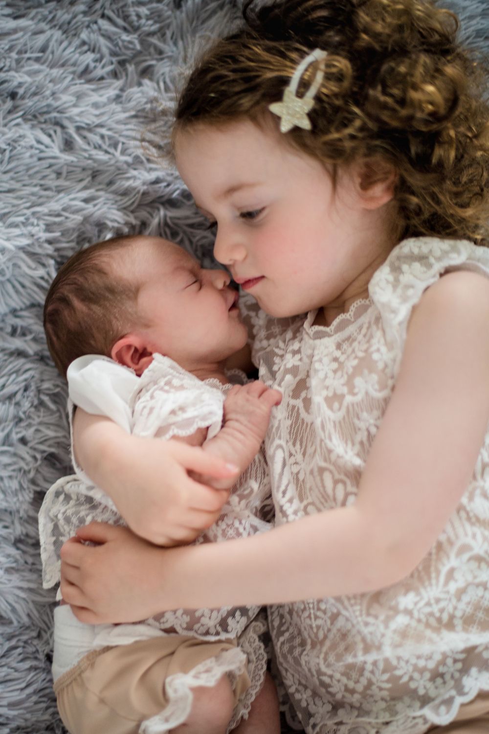 Big sister holding little sister in beautiful matching outfits. The newborn session took place in Zurich.