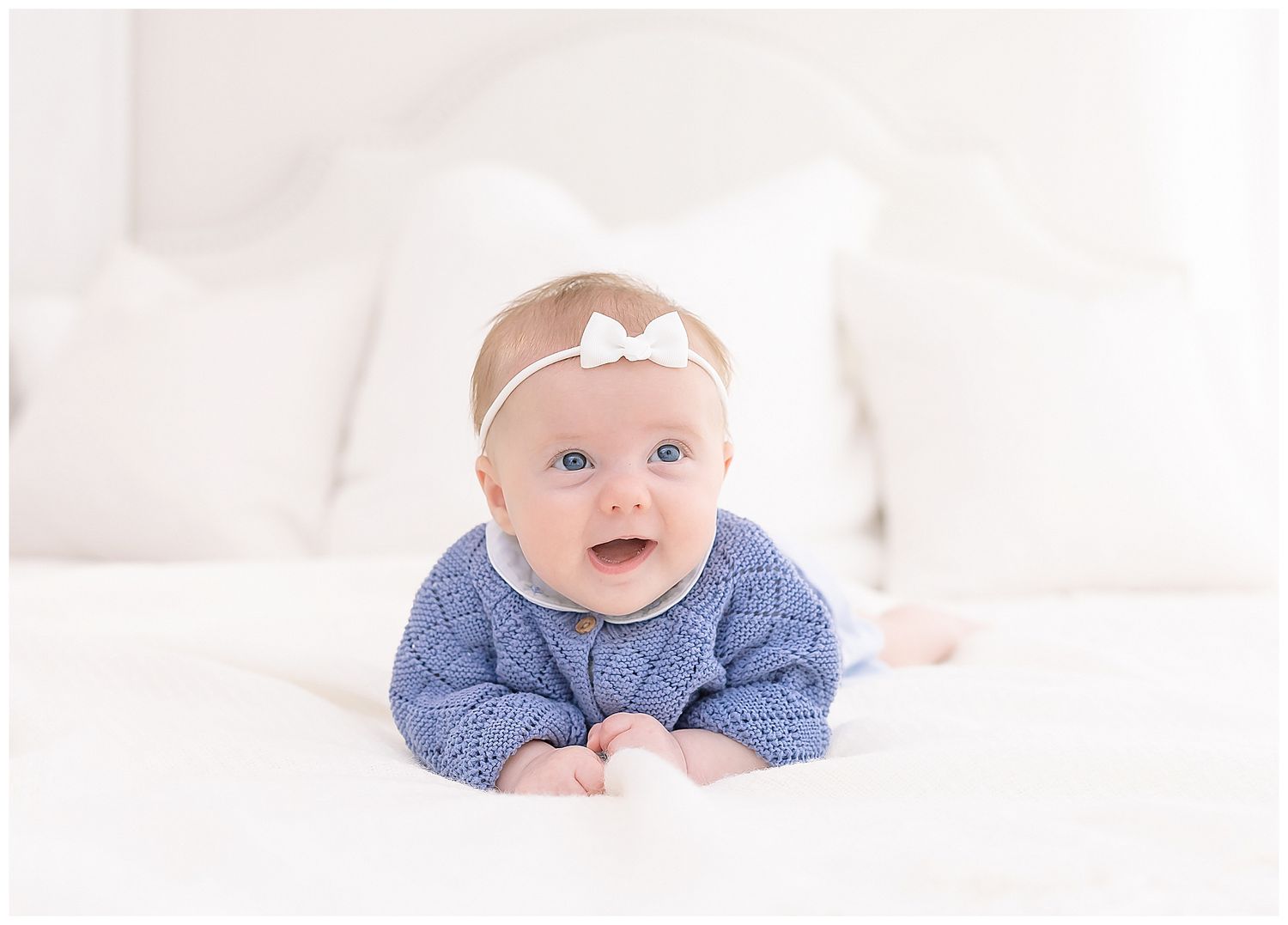 baby girl in blue sweater smiling, pillows, blankets, chattanooga newborn first year photographer, motherhood photograph