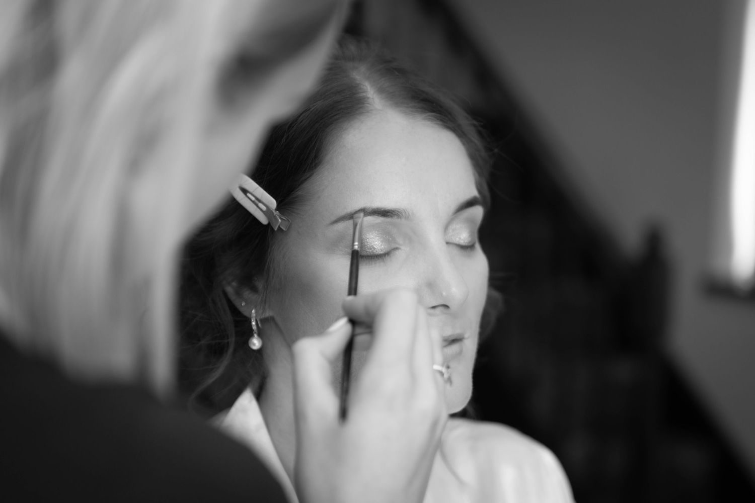 Close-up black and white shot of makeup being applied to an eye.