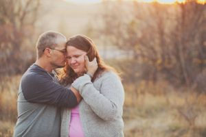 Intimate couple shares tender moment together at sunset in rustic outdoor setting.