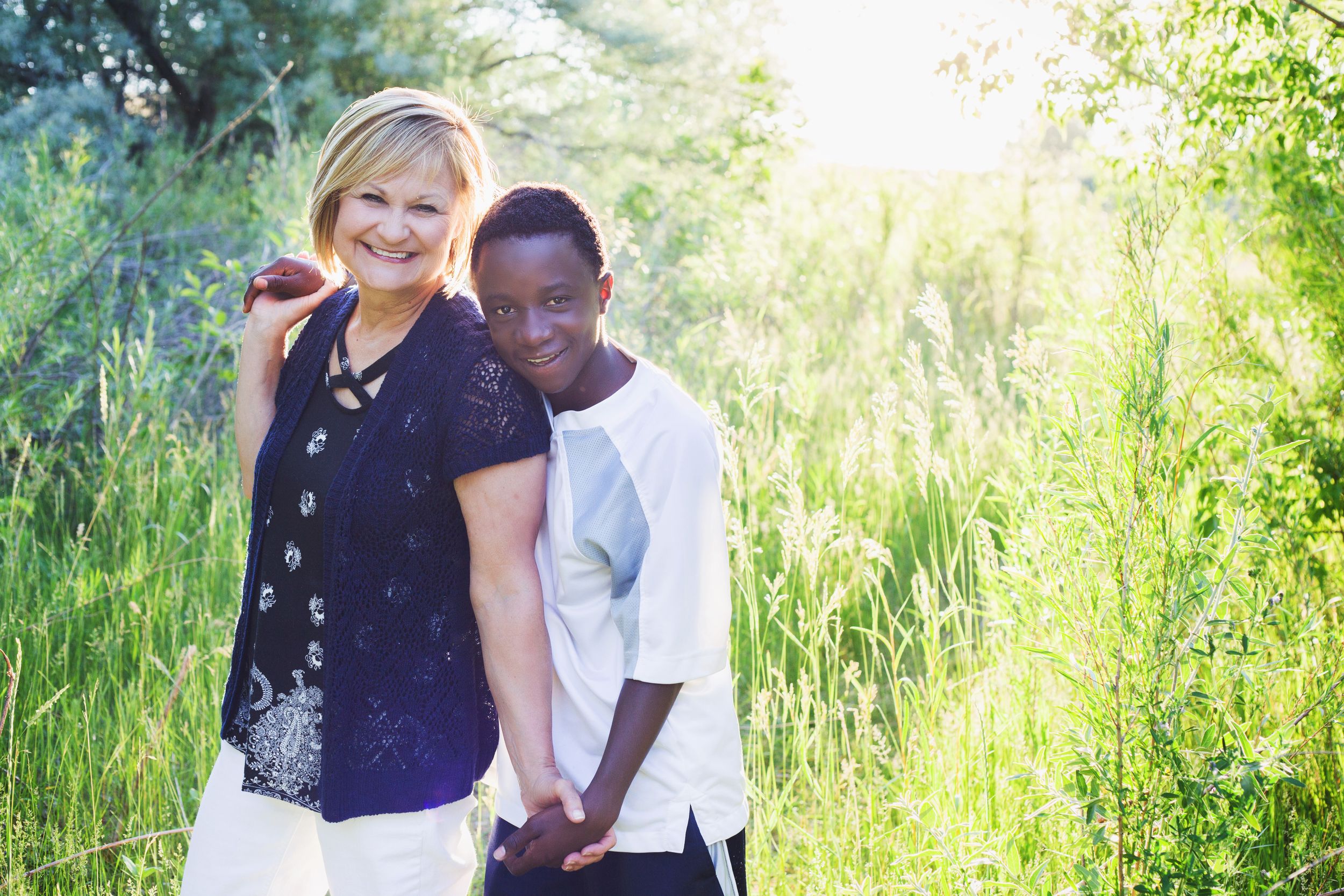 Intimate portrait of two people embracing in a sunlit field of tall grass.