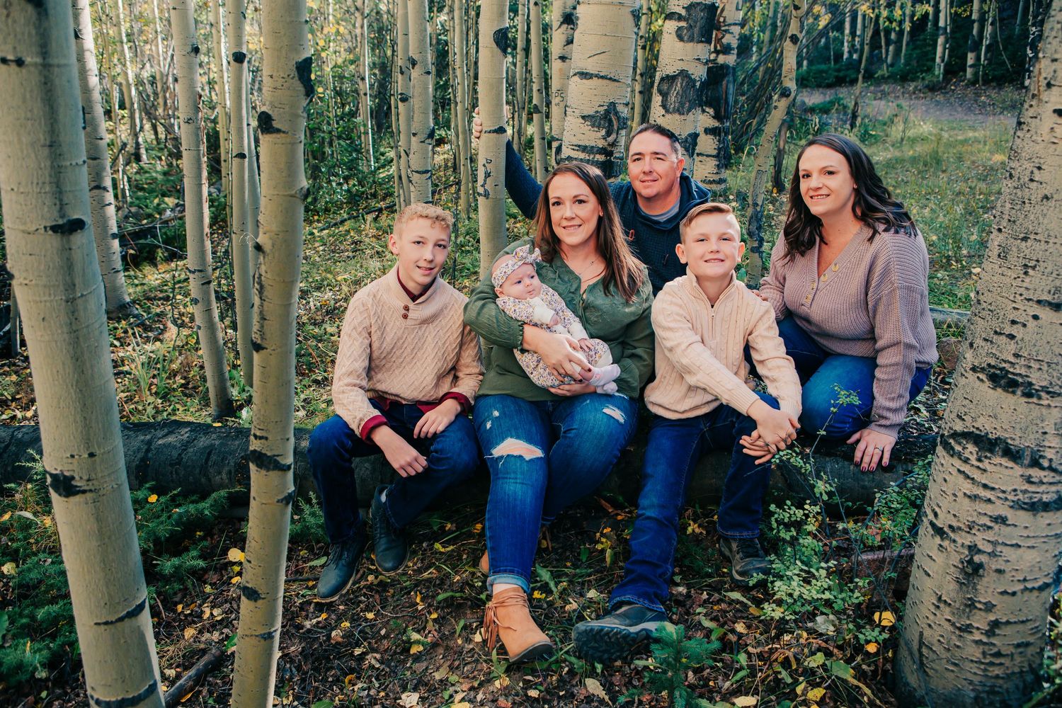 Family group sitting together among aspen trees in autumn.