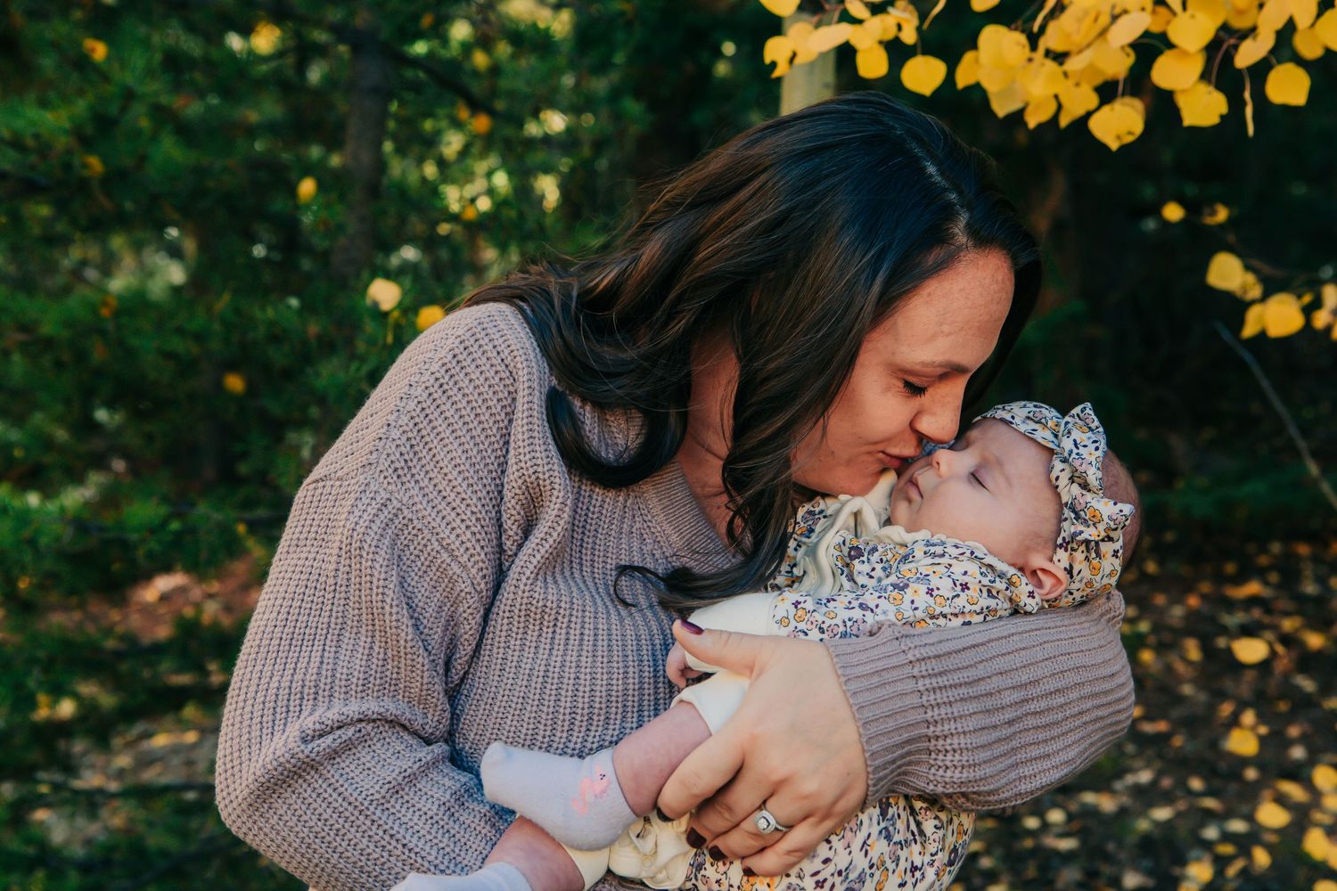 A tender moment between parent and baby surrounded by fall foliage.