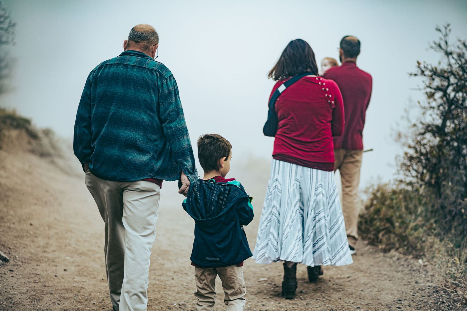A family takes a walk together on a winding dirt path through nature.