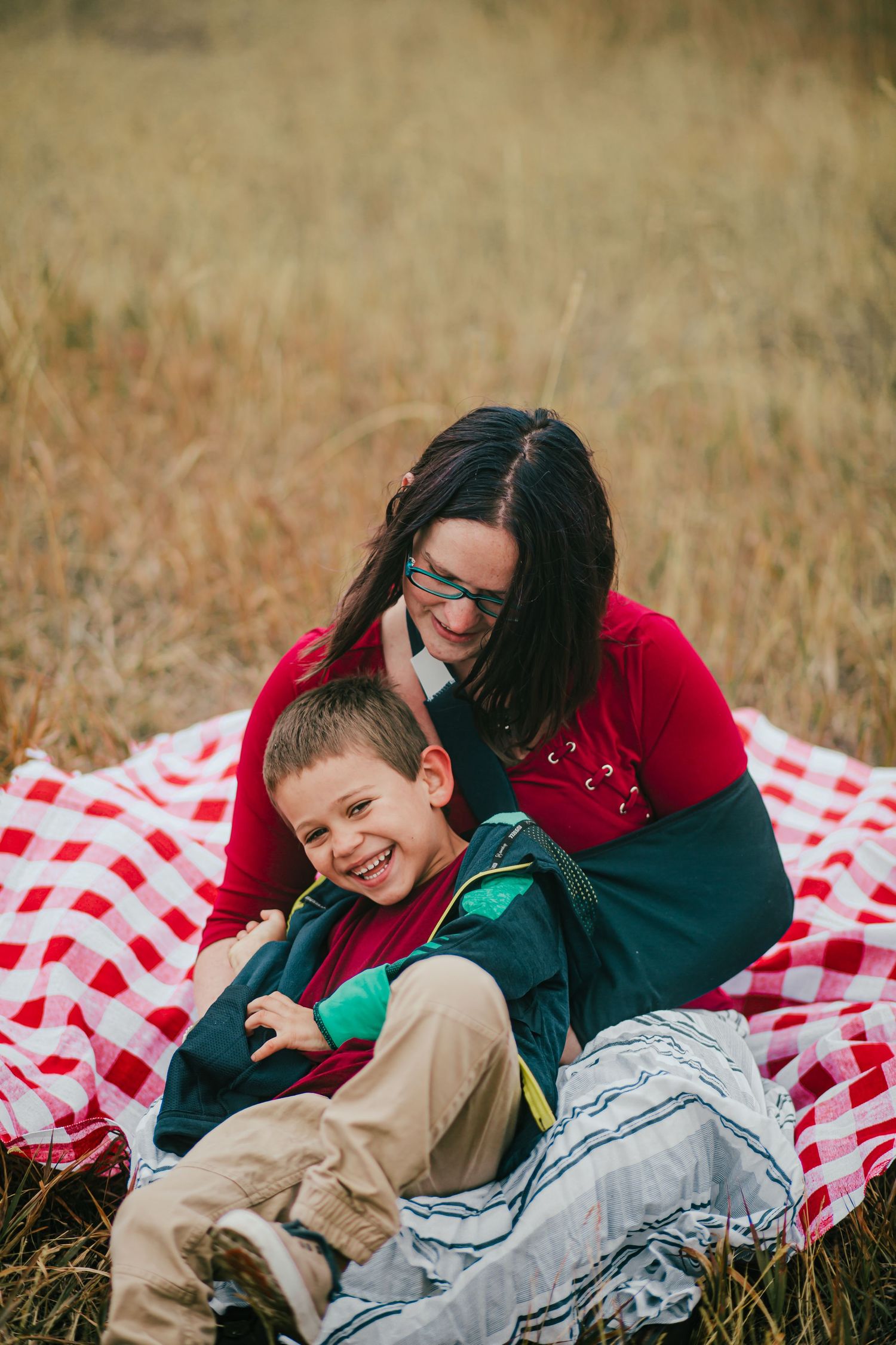 A joyful moment shared on a red and white checkered picnic blanket in tall grass.