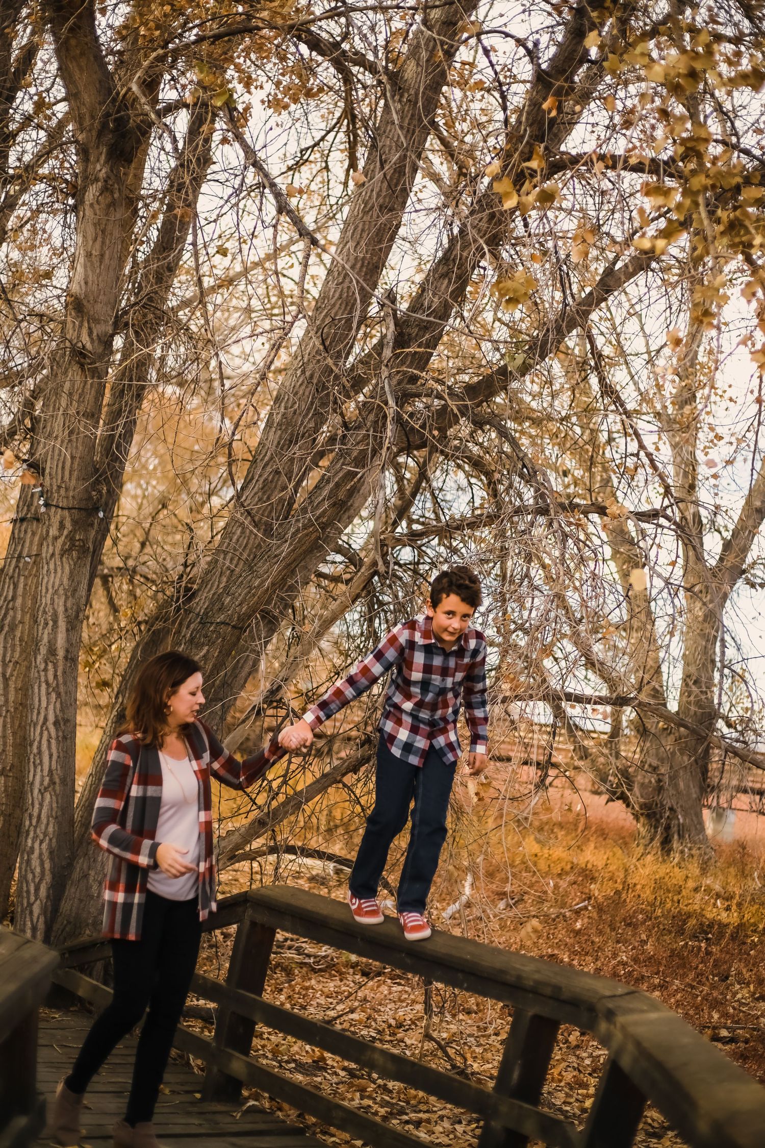Family photo on wooden bridge with fall trees in background.