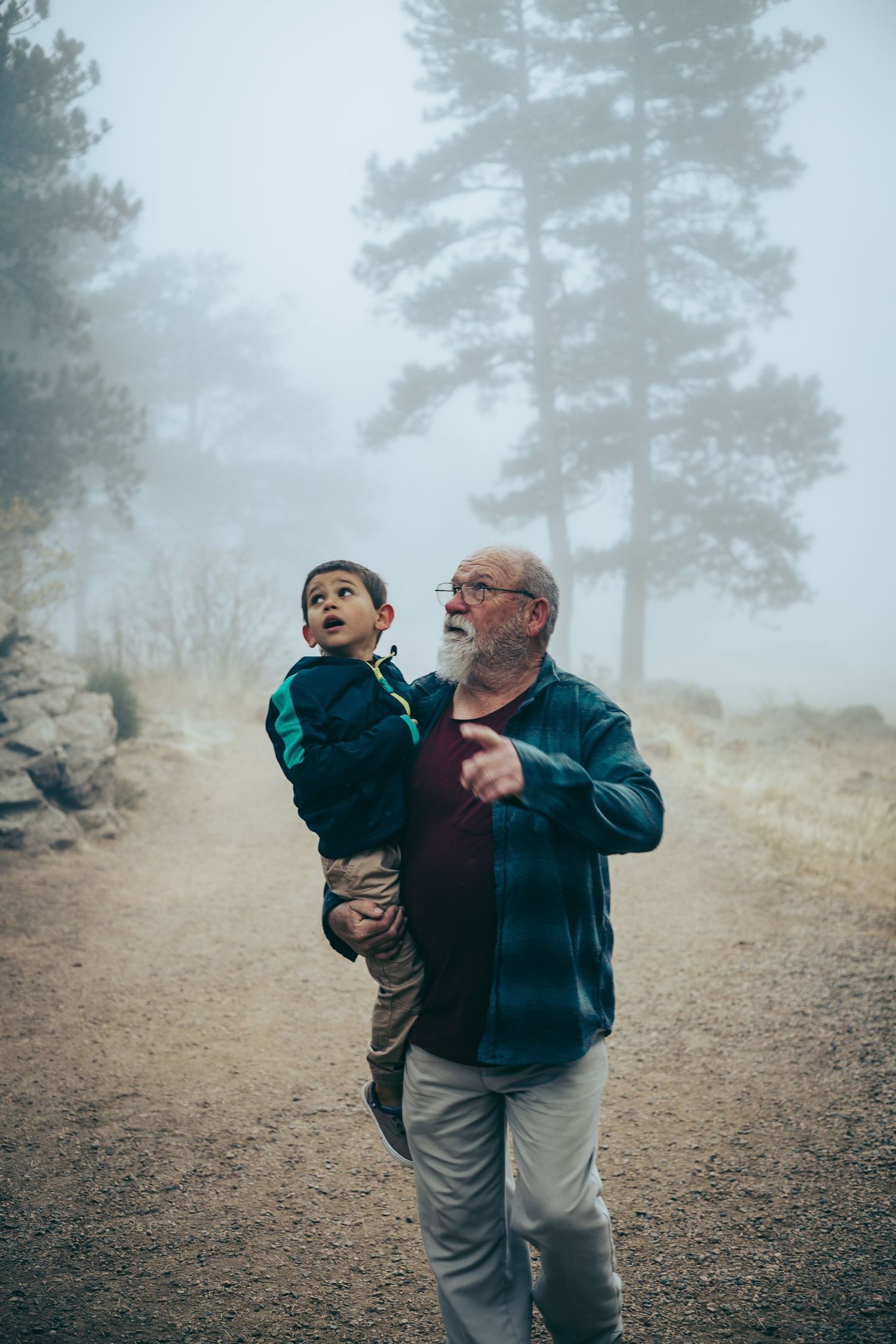 A caring moment shared between two generations while exploring a misty mountain trail.
