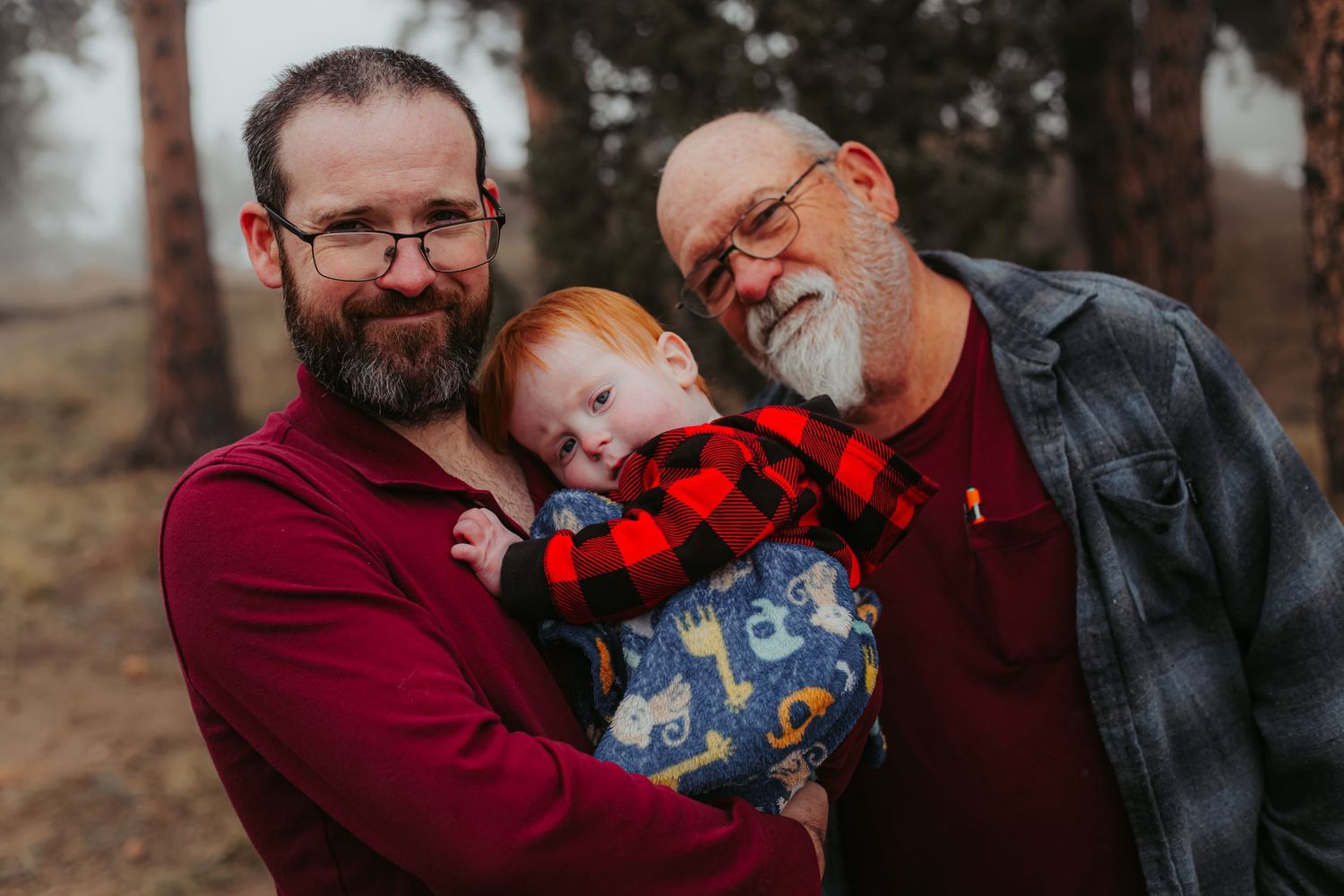 Three generations share a close moment together outdoors on a foggy winter day.
