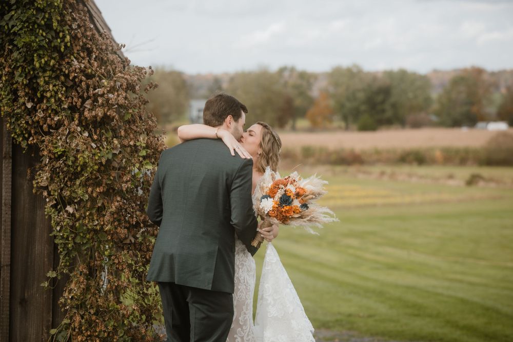 A romantic wedding portrait against an autumn landscape with ivy-covered walls.