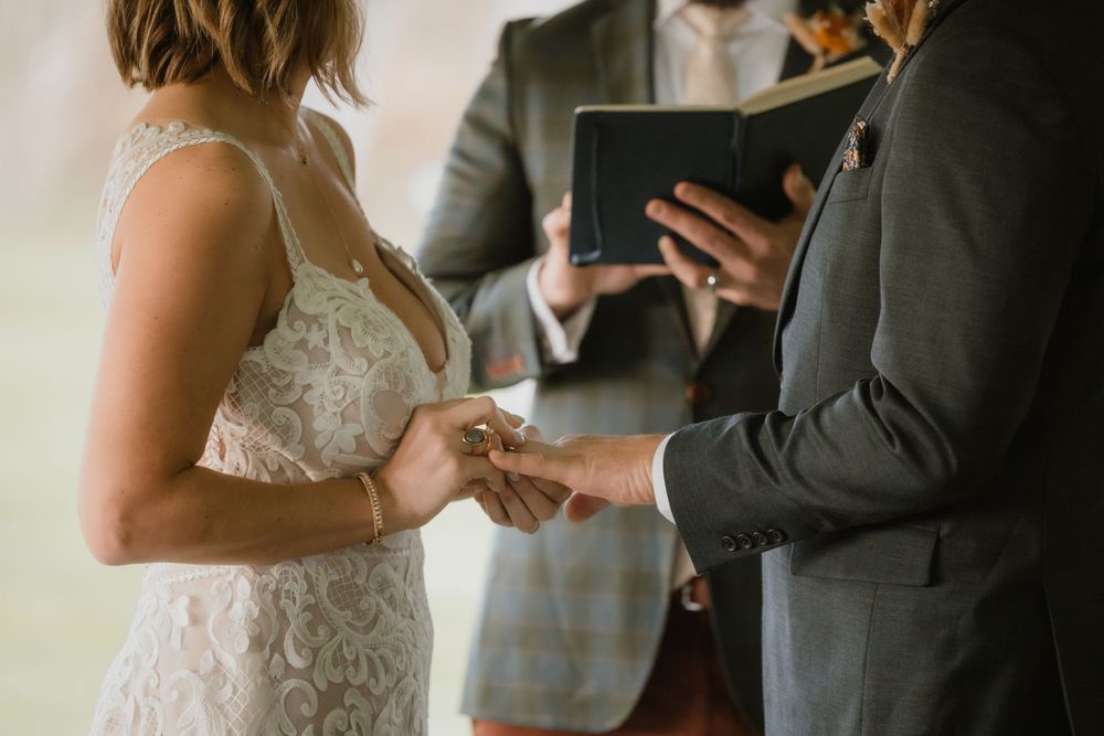 Close-up of wedding ring exchange during an intimate ceremony.