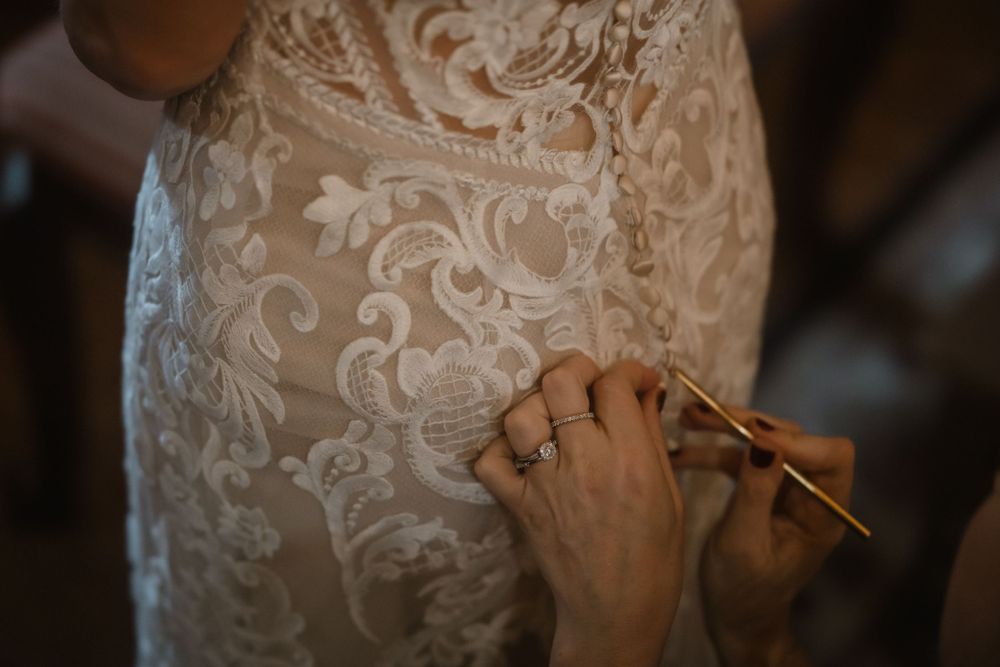 Close-up shot of hands making final adjustments to a lace wedding dress.