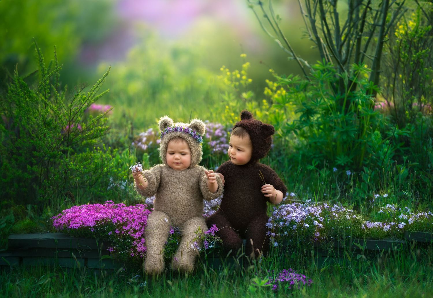 Two children in animal costumes playing in garden with purple flowers.