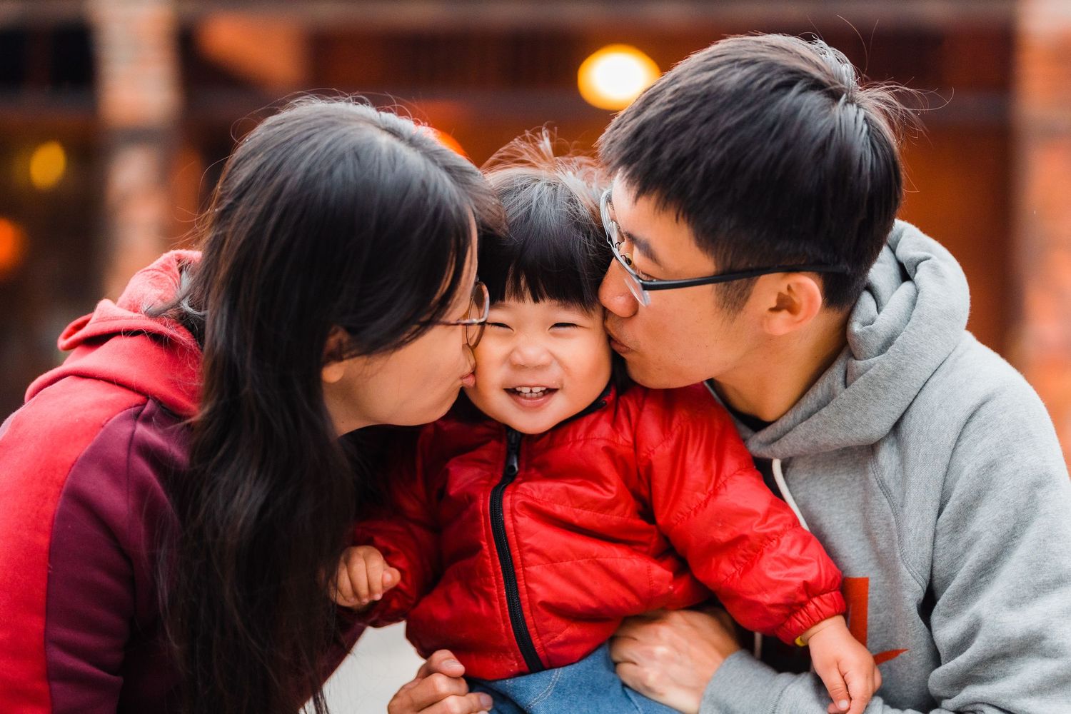 Parents sharing joyful moment with young child in cozy indoor setting.