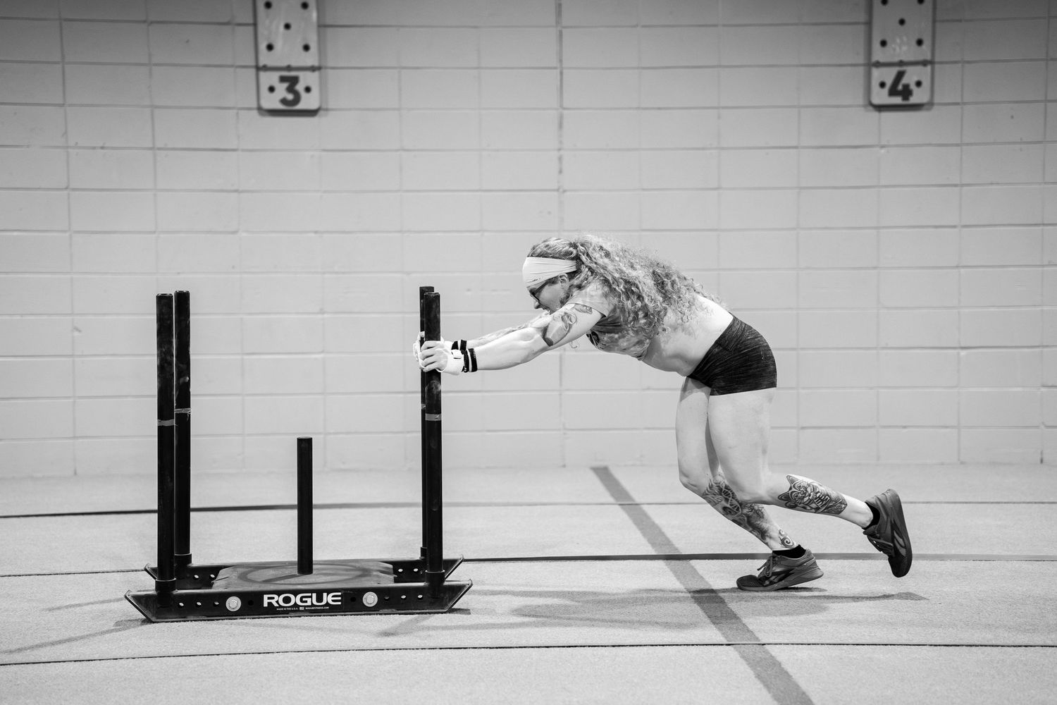 Athletic figure in dynamic motion leaping over training hurdles in black and white.