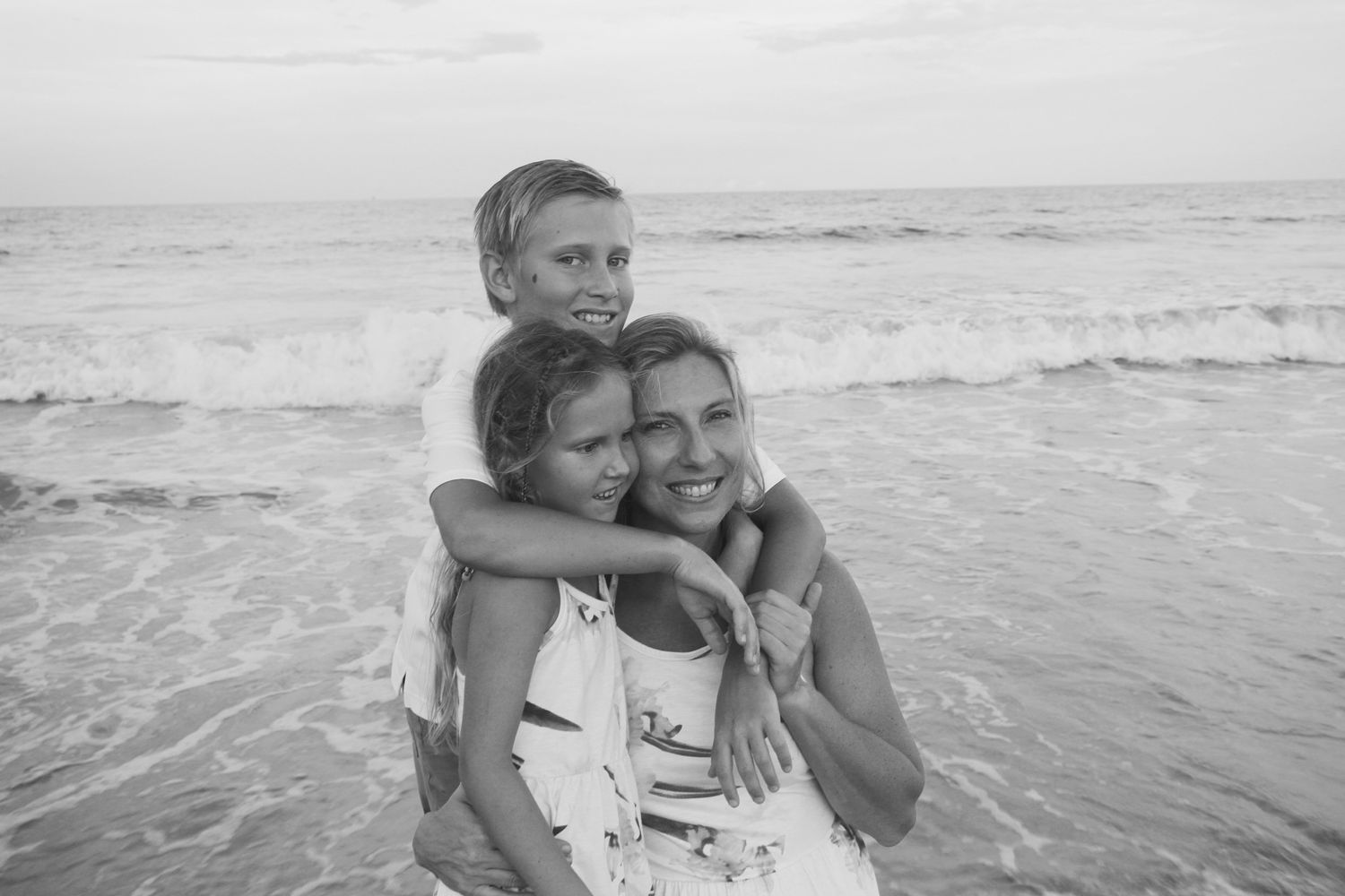 mother and kids playing in the waves and hugging