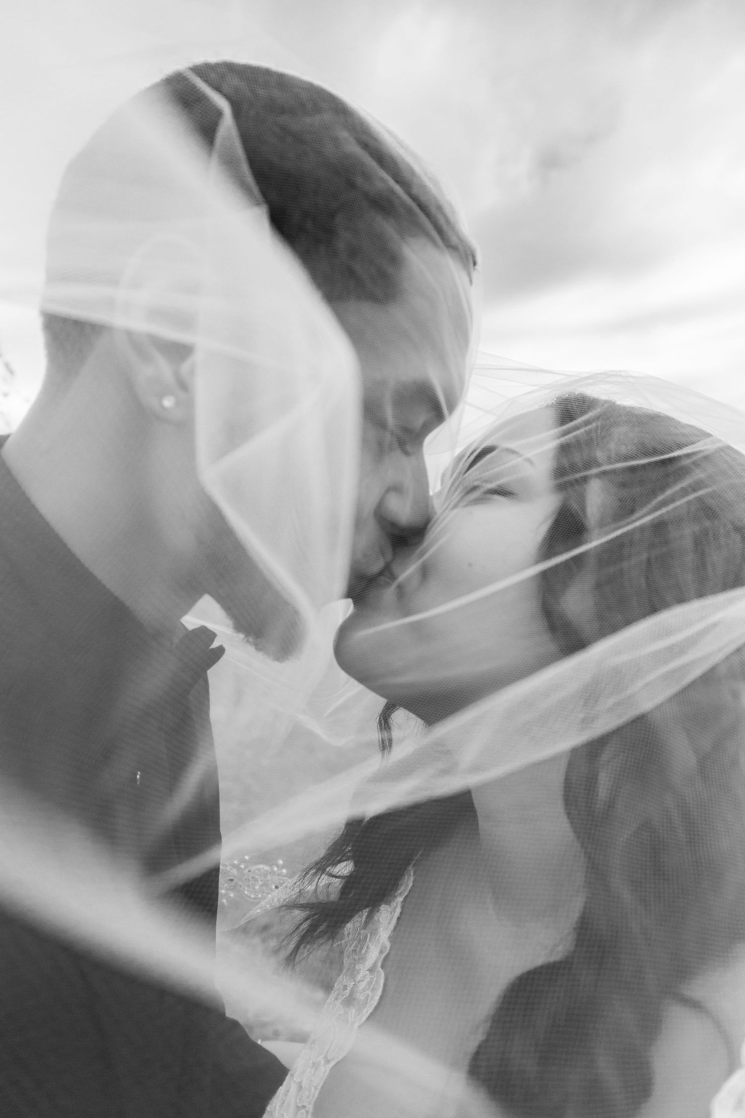 Romantic black and white portrait through a veil showing an intimate moment.