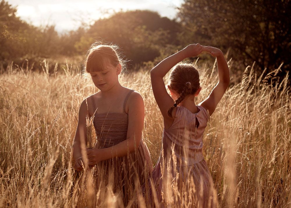 Two sisters playing in long golden grass