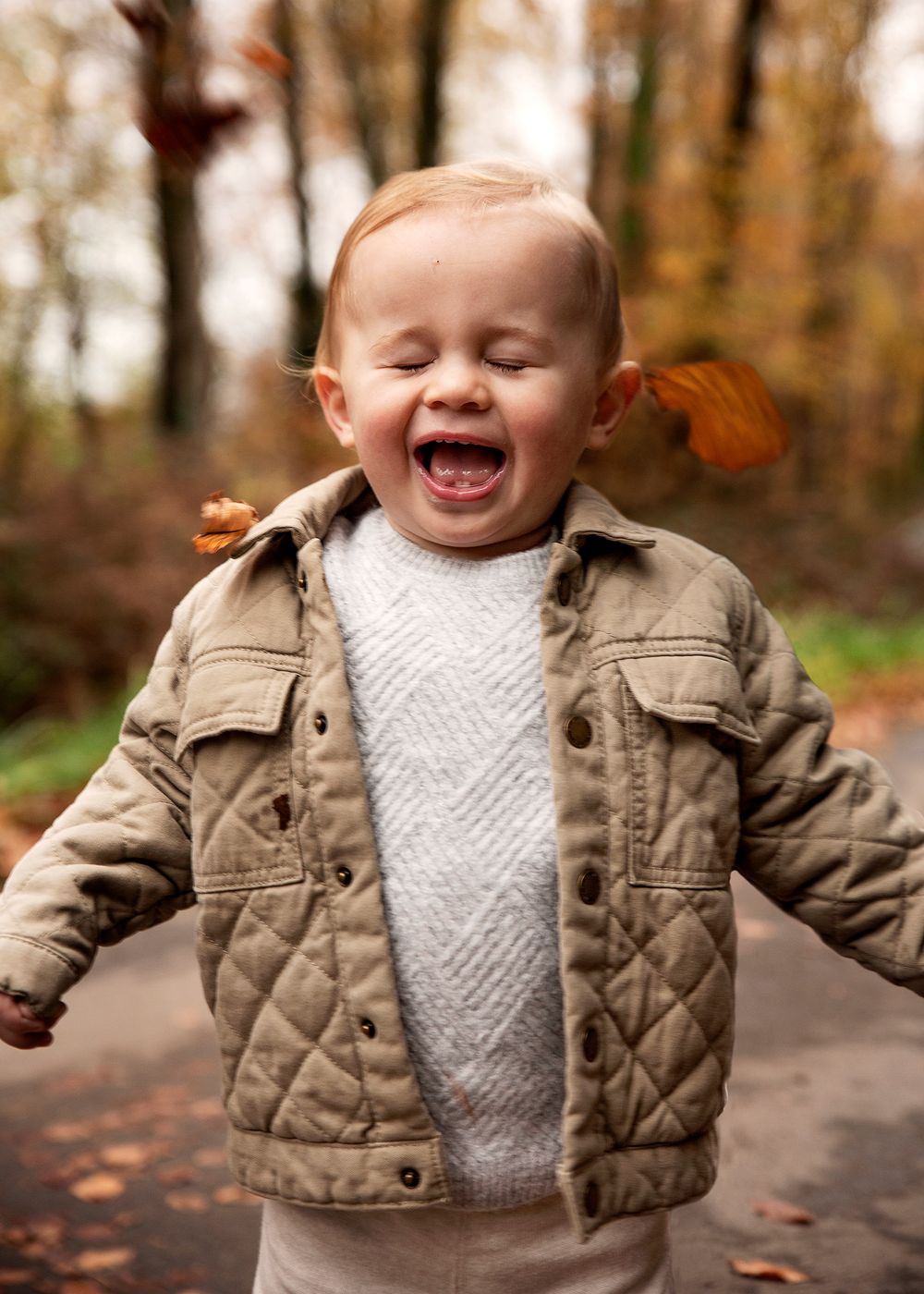 Toddler throwing leaves in the woods