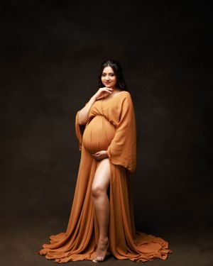 Glamorous maternity photo featuring a billowing orange dress with dramatic pose.