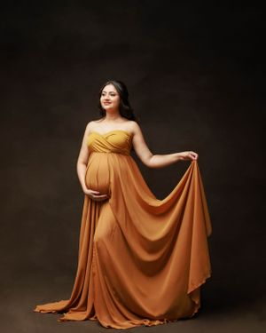 Pregnancy photo showcasing flowing orange maternity gown with sweetheart neckline.