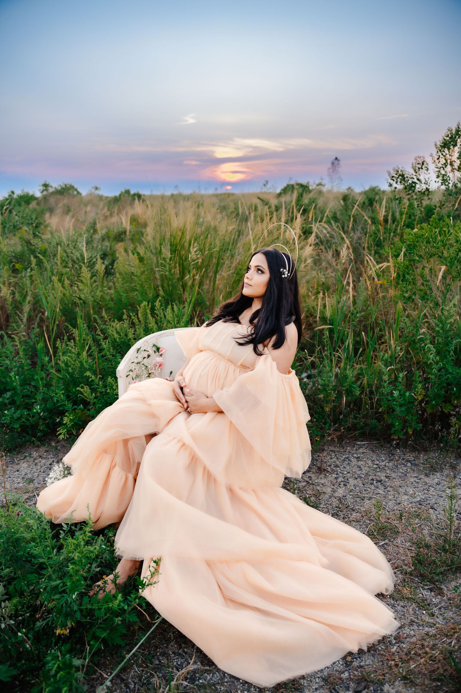 pregnant woman holding belly and looking to the sky in field in Staten Island, NY