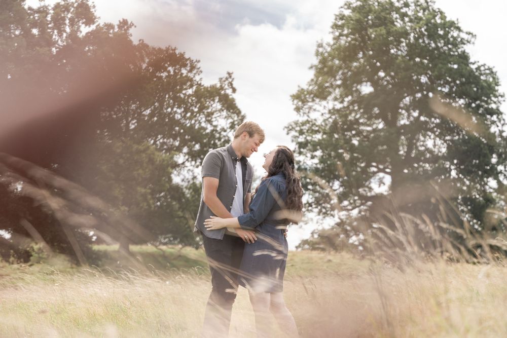 Romantic moment captured in a sunlit field with tall grass swaying in the breeze.