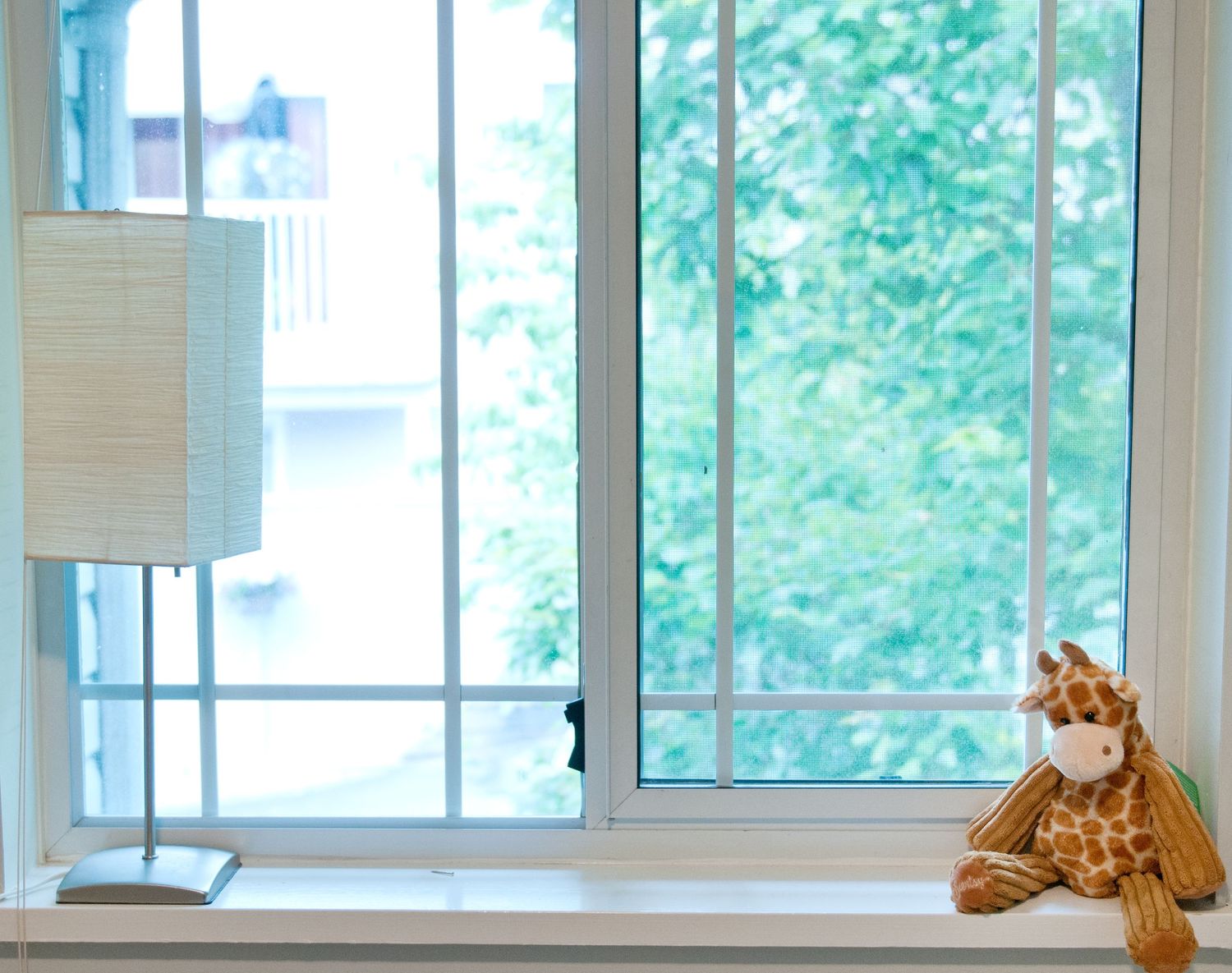 Bright window with white trim and a single stuffed tiger toy sitting on the ledge.