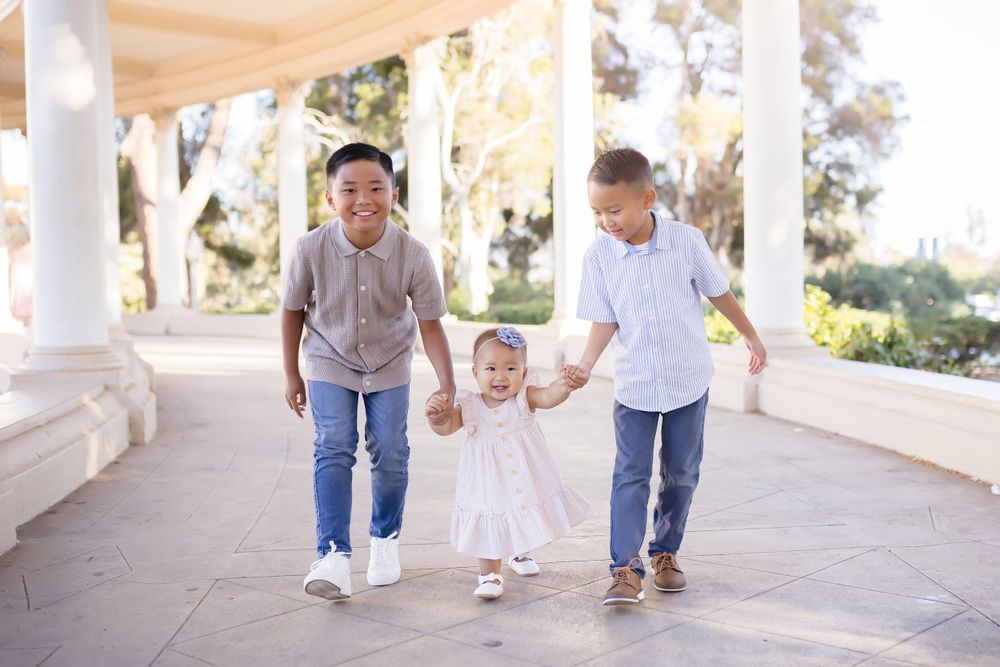 Three people walk hand in hand along a covered outdoor walkway.