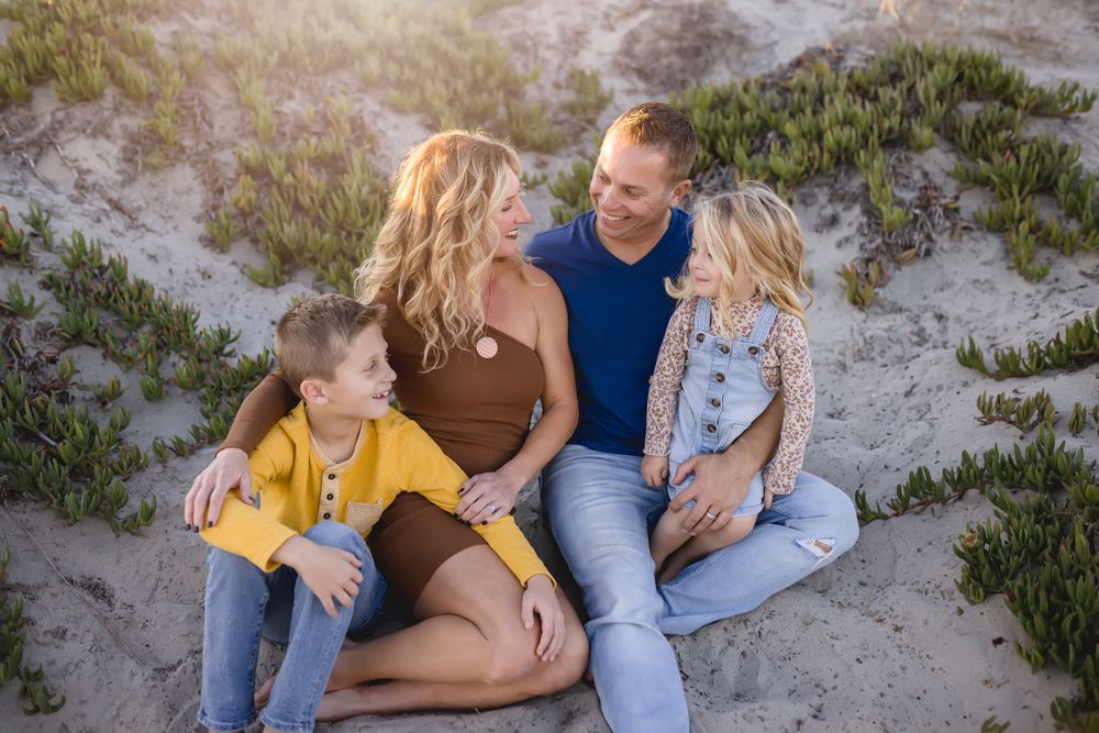 A casual family portrait on sandy dunes during golden hour.