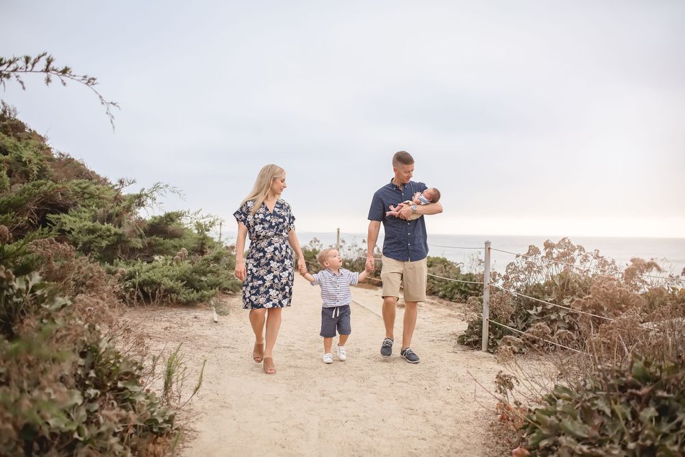 A family walks together on a coastal path during a sunset beach outing.