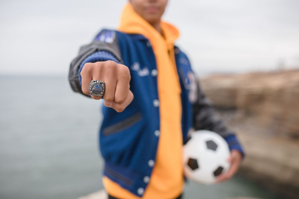 Close up of a sports ring and soccer ball held against an ocean backdrop.