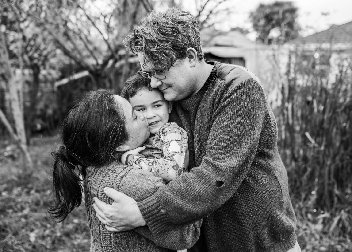 An intimate family moment shared outdoors in a winter garden setting.