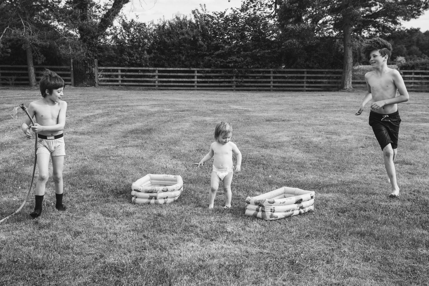 Three people stand in a grassy field with game equipment between them.