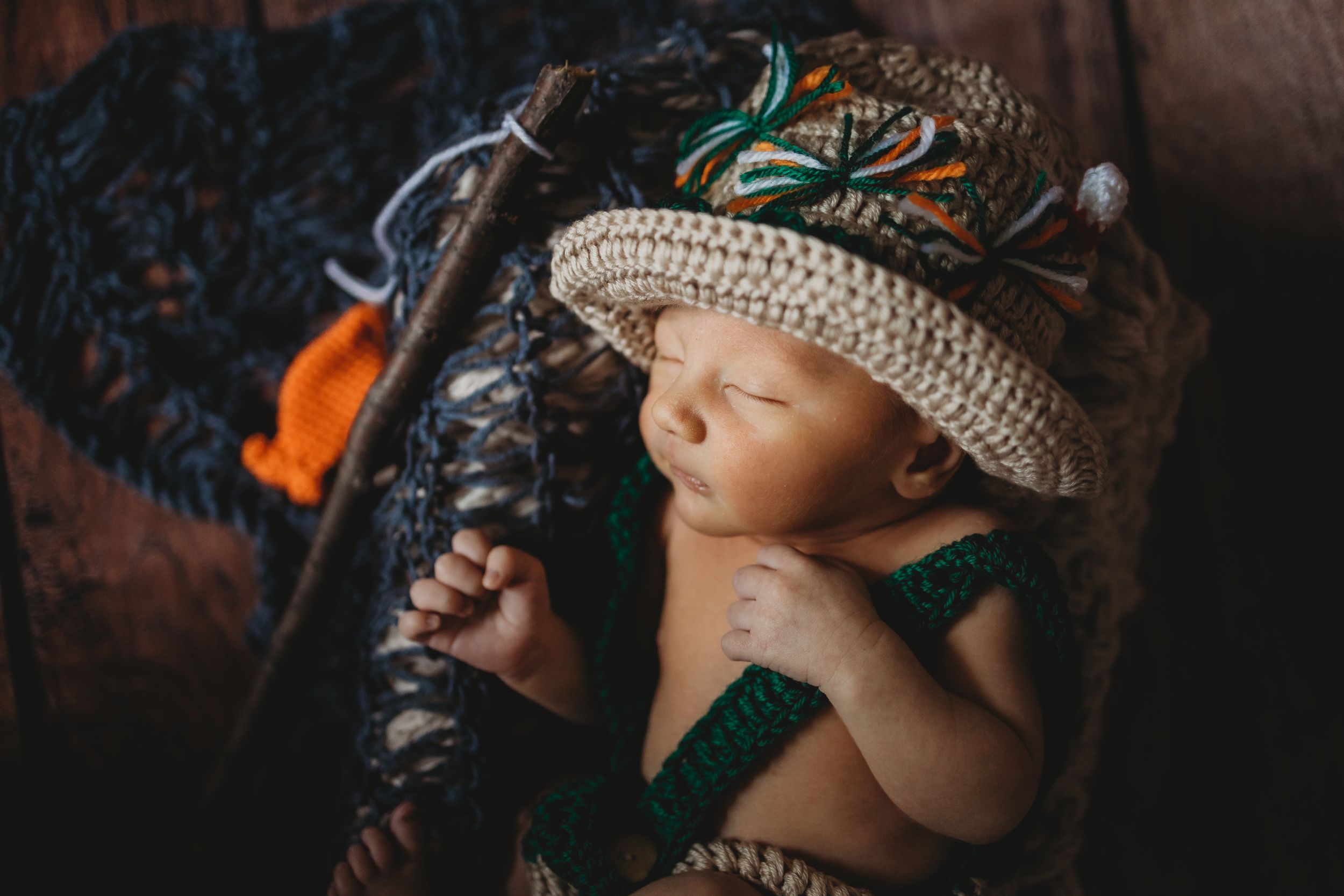 Sleeping baby wearing crochet hat on patterned fabric.