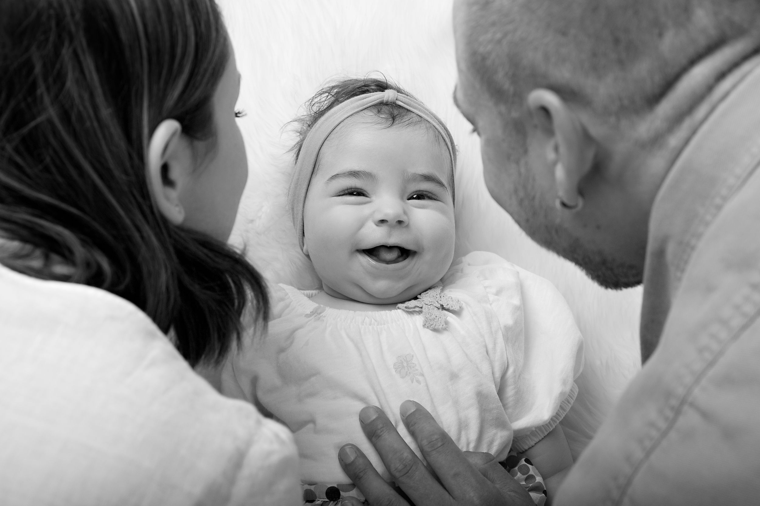 Black and white photo of a joyful baby surrounded by loving adults.