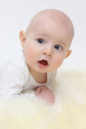Close up of baby in white polka dot outfit lying on yellow fabric.