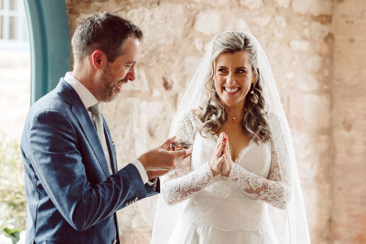 Candid wedding moments captured against a stone wall backdrop.