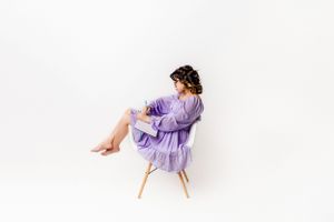 12 year old birthday photoshoot by drawing and wearing purple dress with white background.