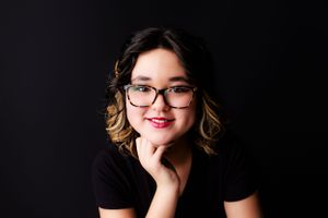 12 year old girl poses for birthday photoshoot with black background.